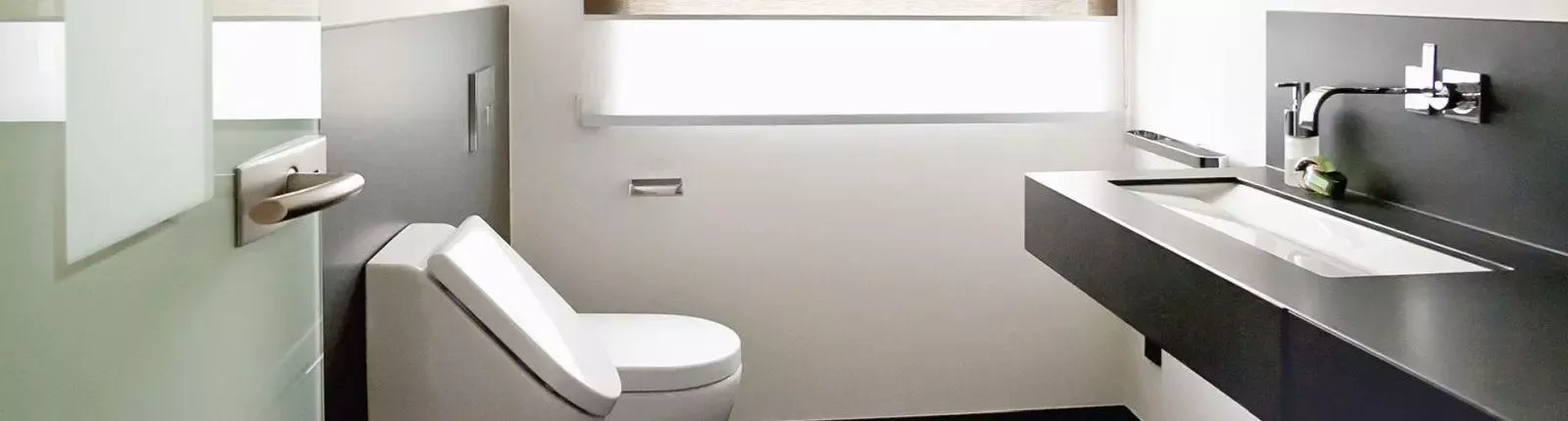 Modernes Gäste-WC mit wandhängendem WC, schwarzem Waschtisch mit Aufsatzarmatur und großem Fenster für viel Tageslicht