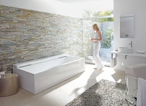 Eine Badewanne vor einer Natursteinwand.
