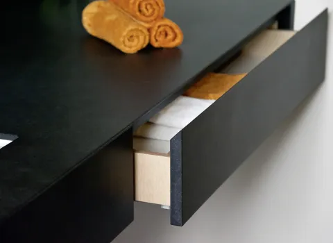 Detailaufnahme im Gäste-WC: Maßgefertigte Schublade im Waschtisch mit edler schwarzer Oberfläche und hochwertigem Innenausbau – elegantes Stauraum-Design.