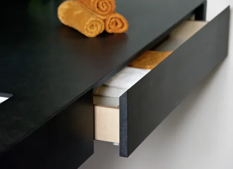 Detailaufnahme im Gäste-WC: Maßgefertigte Schublade im Waschtisch mit edler schwarzer Oberfläche und hochwertigem Innenausbau – elegantes Stauraum-Design.