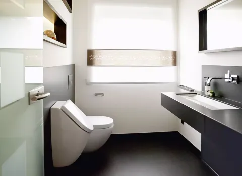 Exklusives Gäste-WC mit modernem Waschtisch aus dunklem Naturstein, wandhängendem WC und stilvollen Akzenten – minimalistisches Design von Rawe.