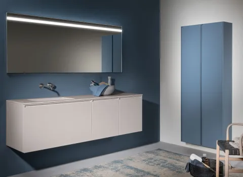 Modernes Badezimmer von Stocco mit schwebendem, hellem Waschtisch, beleuchtetem Spiegel und blauem Hochschrank.
