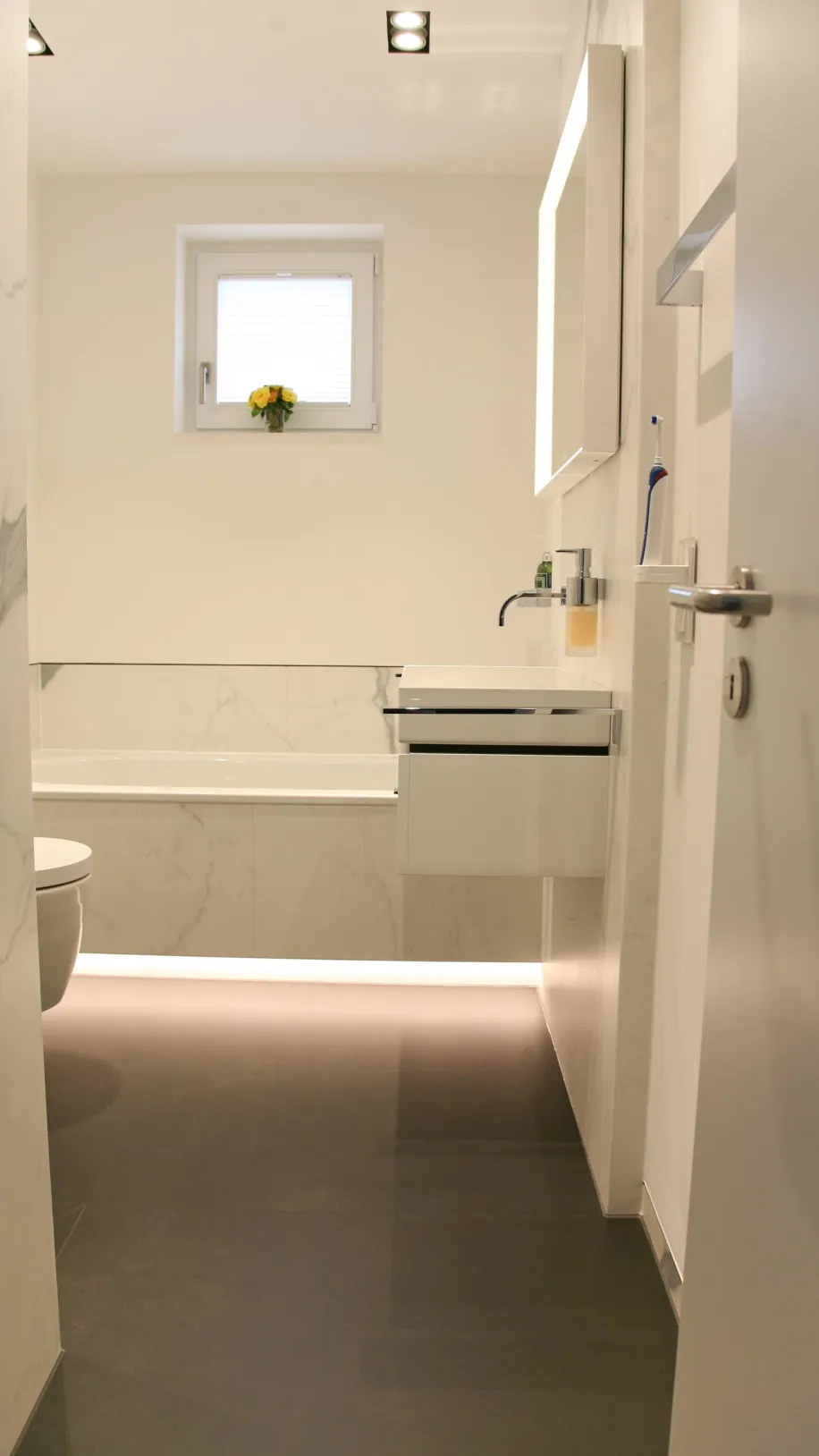 Elegantes Badezimmer mit edlem Marmor, moderner Badewanne und stilvollem Waschtisch. Helles, minimalistisches Design mit Akzenten aus Naturstein und integrierter Beleuchtung.