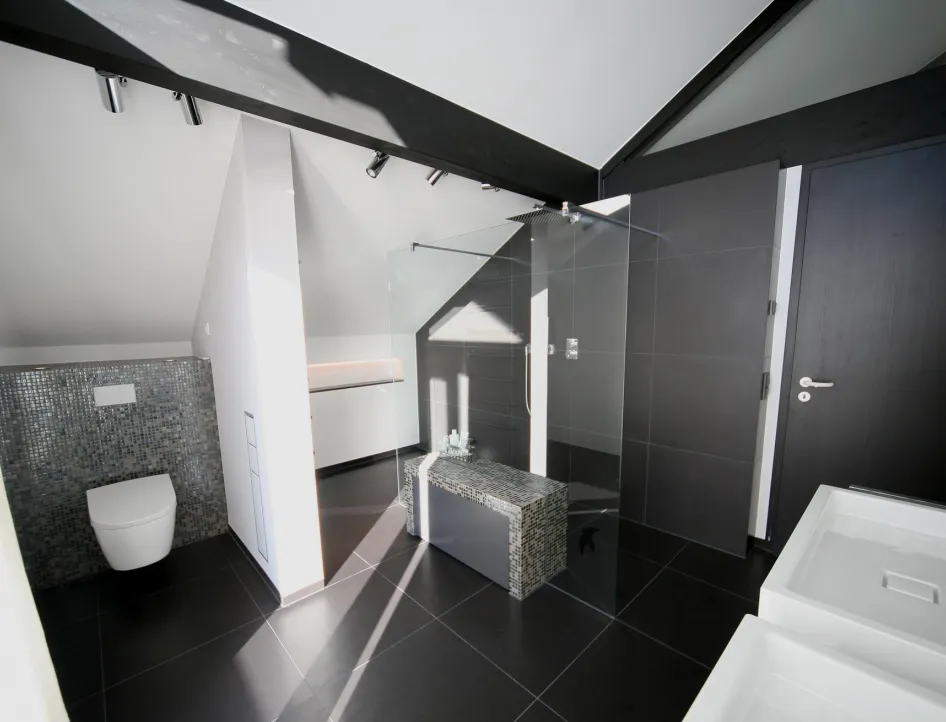 Modernes Dachbad mit offener Walk-In-Dusche, stilvoller Mosaikverkleidung und klaren Linien. Elegantes Design mit dunklen Fliesen und hochwertiger Ausstattung.
