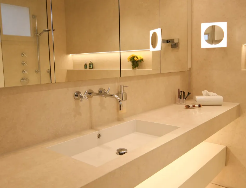 Modernes Badezimmer mit maßgefertigtem Naturstein-Waschtisch, integriertem Spiegel und stilvoller Beleuchtung. Elegantes Design mit hochwertigen Armaturen und minimalistischer Ästhetik.
