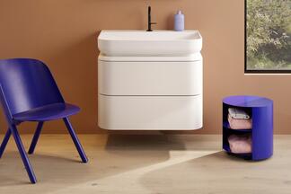 Blaue Sitzmöbel flankieren einen weißen Waschtischunterschrank.