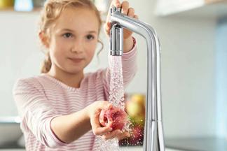 Kind wäscht Obst unter Wasserhahn